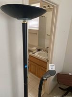 Tall black torchiere floor lamp with bowl-shaped top shade and brass/gold accents next to shorter black flexible neck floor lamp with round base.