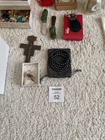 Close-up showing various jewelry like metal cross pendants, black beaded bracelet, carved animal figures, and a small box.