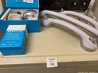 Loaded view of the Redefine AMP MD micro-exfoliating roller box with device and accessories alongside three white plastic grab bars with suction cups