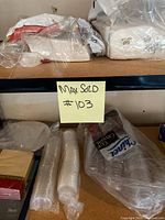 Photo of plastic cups, disposable plates, napkins and some miscellaneous items on a garage rack shelf.