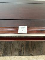 Close up of the top surface showing wood grain and carved detailing along edge.