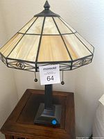 Full view of Tiffany style lamp showing stained glass octagonal shade and metal base with pull chains.