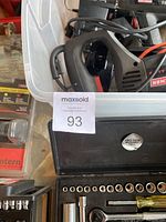 Close up image of socket set with numerous chrome sockets and a metal tool box labeled Pro-Tech inside a plastic bin.