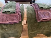 Set of green and purple towels folded and stacked showing bath towels, hand towels, and washcloths.