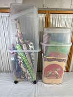 Tall and shorter clear plastic containers filled with partially used Christmas wrapping paper rolls
