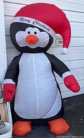 Full view of large inflatable penguin Christmas decoration with Santa hat and 'Merry Christmas' text.