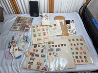 Wide view of stamp collection including loose stamps, album pages with vintage stamps, and folders.