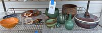 Full view of collection showing various pottery and glass containers on a metal shelf, including bowls, covered pots, and vases in various colors and sizes.