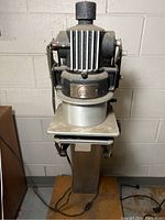 Front view of the vintage photo enlarger showing the enlarger head, lens area, and pedestal stand.