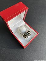 Ring shown inside a red jewelry box with white interior.