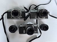 Top view showing three vintage cameras including Nikkormat, STL 1000, and Mamiya TLS with some lenses attached or nearby