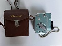 Camera next to original brown leather carrying case with Bauer branding