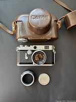 Camera kit laid out: body, lens, hood, front cap, case top and pouch