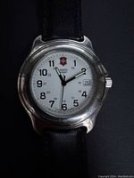 Front view of vintage Swiss Army watch showing white dial with black numbers, Swiss Army logo, and black leather strap.