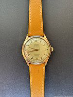 Front view of the vintage Weber automatic watch with tan leather strap and gold filled case on black background.