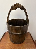 Front view of antique mahogany wood coopered bucket showing wood slats and sturdy handle with curved grip.