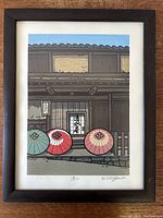 Full view of framed woodblock print hung on wooden background