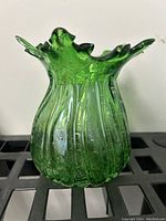 Front view of the green blown glass vase showing the ruffled top and vertical ribbing.