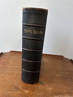 Front view of spine showing black pebble leather, raised bands, gilt “Holy Bible” stamping
