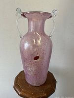 Front view of textured pink-lilac Murano art glass vase with clear handles on a wooden surface.