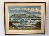 Full view of framed oil painting showing mountain landscape, ocean waves, clouds and linen-lined wood frame
