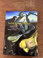 Front cover of the coffee table book with vibrant surreal oil painting artwork by Salvador Dali, titled 'The Dali Museum Collection'.