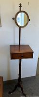 Full view of the Victorian carved wood butler table de toilette stand with pedestal base, single drawer, and round adjustable mirror.
