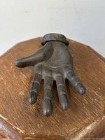 Close-up of the cast-iron hand palm hanger showing the fingers and palm texture resting on a wooden surface.