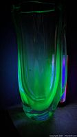 The vase glowing bright green under UV light showing its uranium glass properties.
