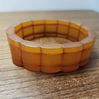 Close-up image showing the butterscotch amber bracelet laid flat on wood surface, highlighting the polished rectangular amber segments and elastic assembly.