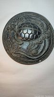 Front view of the round bronze plaque depicting a dragon entwined with a turtle shell with swirling cloud and wave patterns in the background.
