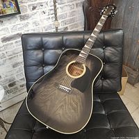 Full front view of guitar on chair showing grey burst finish and black pickguard