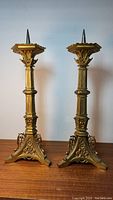 Front view of the pair of antique spiked brass candlesticks showing detailed craftsmanship and full height.