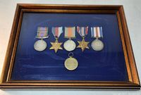 Framed display showing six medals on blue felt backing