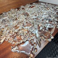 Large pile of mixed crystal prisms and bead strands on wooden surface