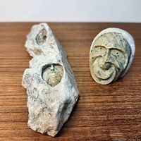 Overview of both soapstone carvings on wooden surface: small bust and rock matrix with two faces