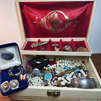 Wide view of open jewelry box containing assorted sterling silver, Murano glass, pearl necklaces, and other costume jewelry.