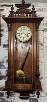 Full front view of oak regulator clock hung on wall