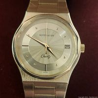 Close-up of watch dial showing silver sunburst finish, crystal hour markers, date window at 3 o’clock and ‘Wittnauer Quartz Swiss’ branding