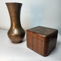 Photo showing both the copper vase and the wood box side by side on a neutral surface
