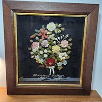 Frontal view of framed floral embroidery sampler on black ground