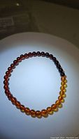 Photo showing natural Baltic amber stretchy bracelet with beads ranging in color from yellow, honey to dark amber.