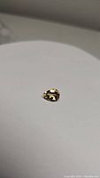 Photo of a pear cut golden citrine gemstone placed on a white surface showing slight reflection and shadow.