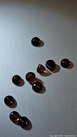 Multiple small round cabochon and bullet cut almandine garnet gemstones arranged on a flat surface showing deep red color and polished finish.