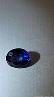 Close-up photo of a loose oval-shaped royal blue sapphire gemstone showing its deep blue color and faceted cut.
