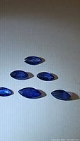 Top view of six marquis cut blue sapphires arranged on a flat surface showing color and cut consistency.