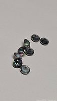 Eight calibrated 4mm round Mystic Topaz gemstones arranged on a flat surface, showing iridescent colors under light.