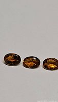 Three natural oval cut tourmaline gemstones showing rare Fanta orange color, arranged side by side on a white background.