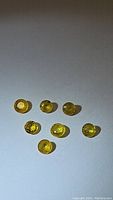 Top-down photo of seven round cut yellow sapphires laid out on white background showing their size and color clarity.