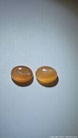Two oval cabochon peach moonstones showing peach color and light reflection.